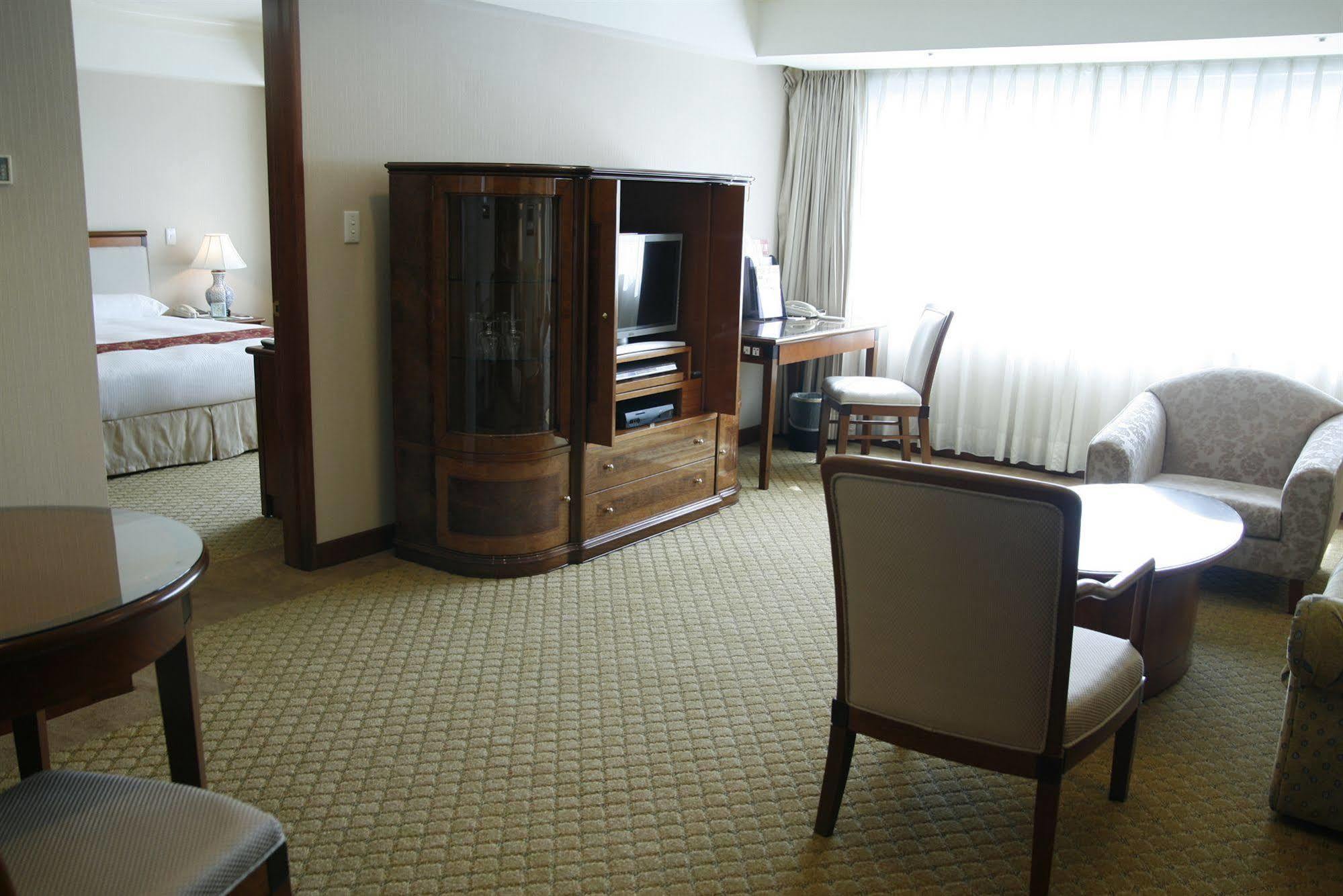 Evergreen Laurel Hotel - Taichung Extérieur photo The photo shows an interior of a hotel room suite. The space includes a living area with several pieces of furniture. There is a coffee table and chairs, creating a comfortable seating area. A wooden cabinet with a TV inside is situated against one w