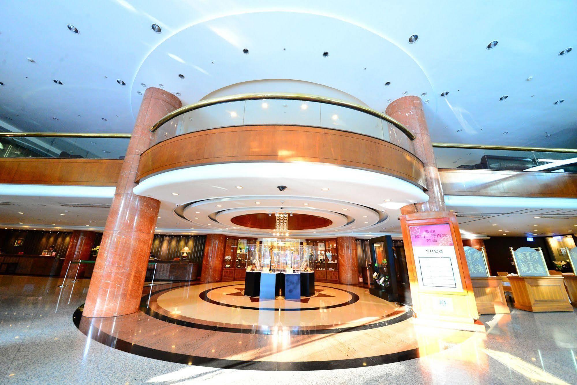 Evergreen Laurel Hotel - Taichung Extérieur photo The photo shows the interior of a spacious lobby area. It features a modern architectural design with polished surfaces and a circular ceiling structure. The walls are accented with wooden panels, and there is a central chandelier hanging from the ce