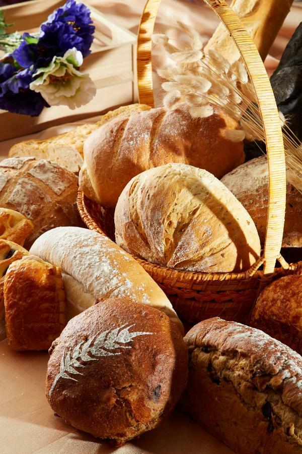 Evergreen Laurel Hotel - Taichung Extérieur photo The photo shows a variety of freshly baked bread arranged in a woven basket. There are different types of bread, including round loaves, baguettes, and crusty rolls, showcasing a range of colors and textures. Some loaves have distinctive patterns or 