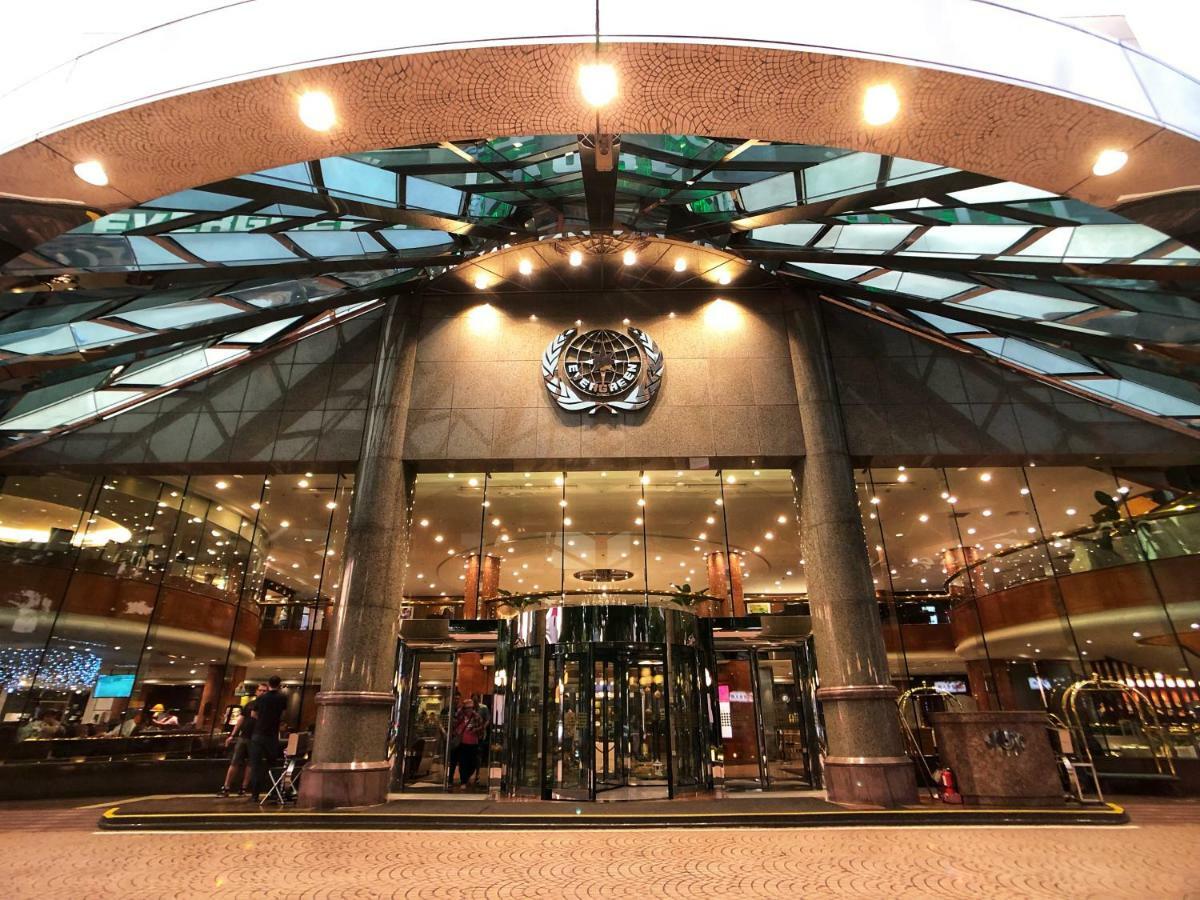 Evergreen Laurel Hotel - Taichung Extérieur photo The image shows the entrance of a modern building, likely a hotel or a luxury establishment. The entrance features a large revolving door surrounded by glass panels. Above the entrance, there is a prominent logo or emblem. The overall architectural d