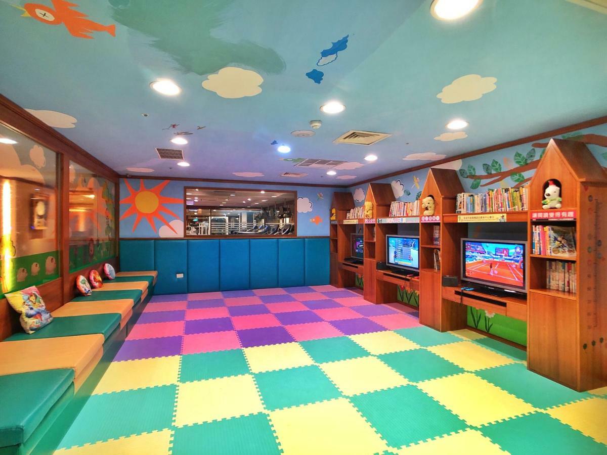 Evergreen Laurel Hotel - Taichung Extérieur photo The photo shows a brightly colored children's playroom or activity area. The floor is covered with large colorful tiles in shades of blue, green, yellow, and pink, creating a playful pattern. The walls have cheerful decorations, including sun and clo