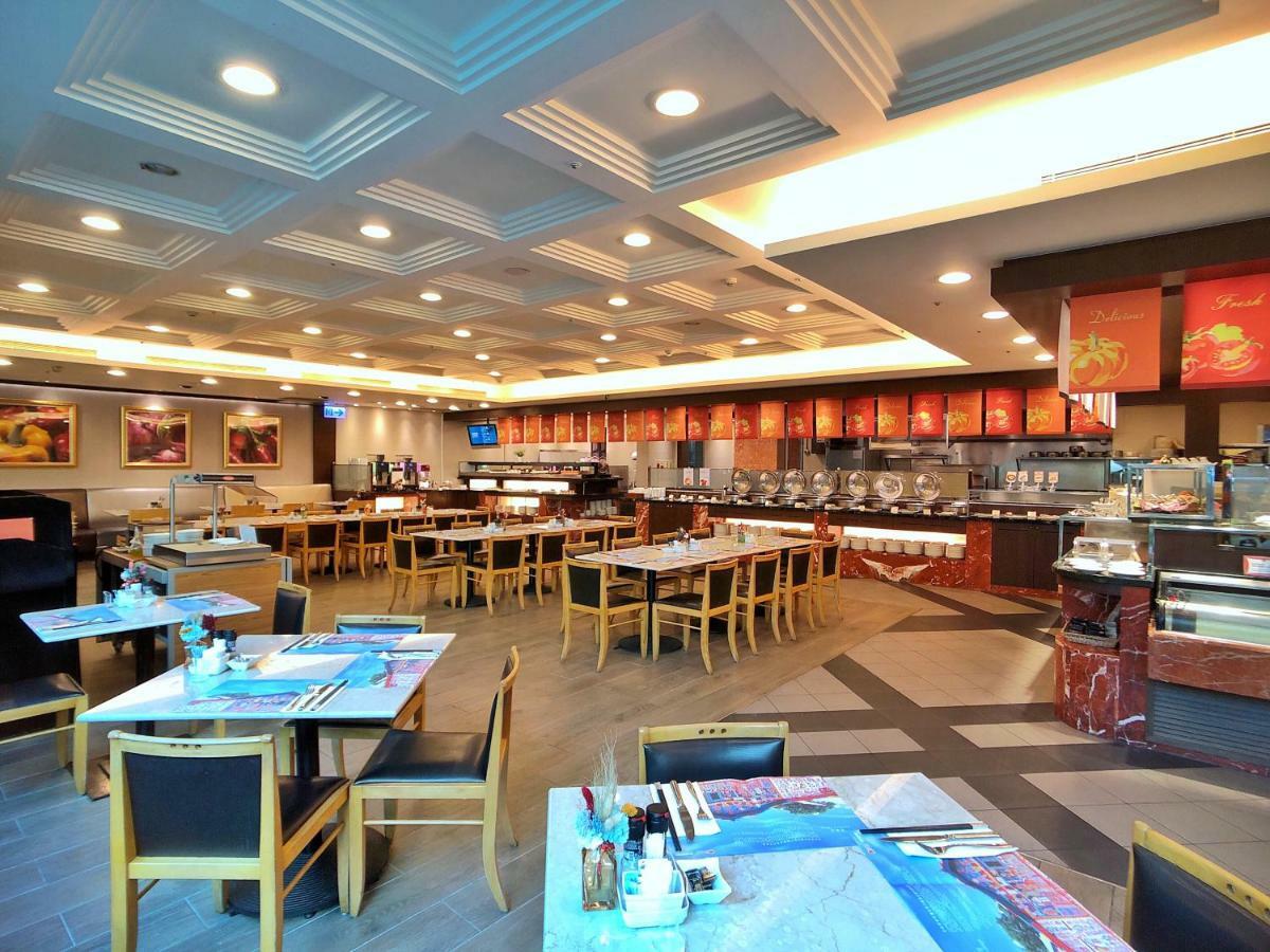 Evergreen Laurel Hotel - Taichung Extérieur photo The photo shows the interior of a restaurant. The dining area features several tables with chairs arranged neatly. The flooring has a contemporary design, and the ceiling is structured with a coffered pattern. There is a buffet area along one wall wi