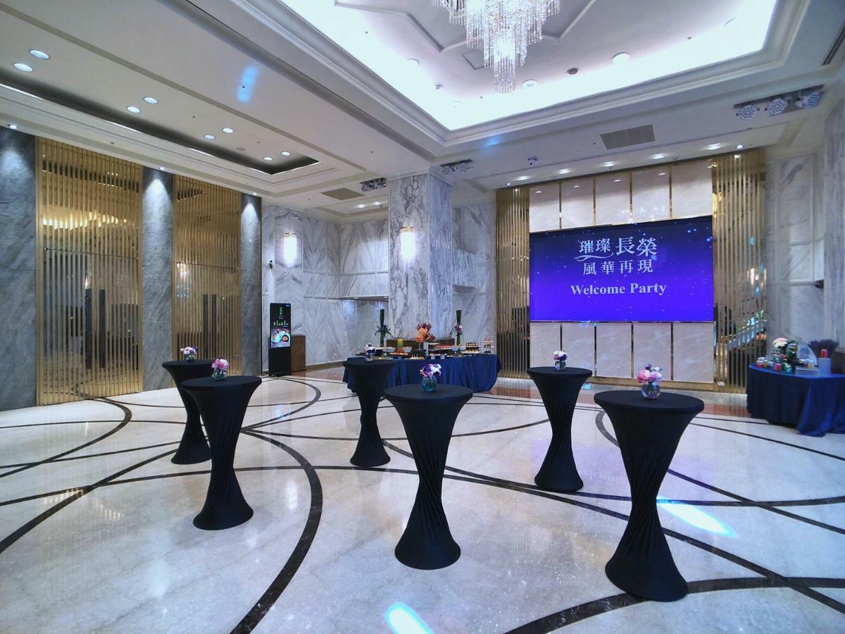 Evergreen Laurel Hotel - Taichung Extérieur photo The photo depicts a spacious and elegantly decorated event space, likely set up for a welcome party. The room features polished marble flooring and tall ceilings, giving it a sophisticated atmosphere. In the center, several round tables with black ta