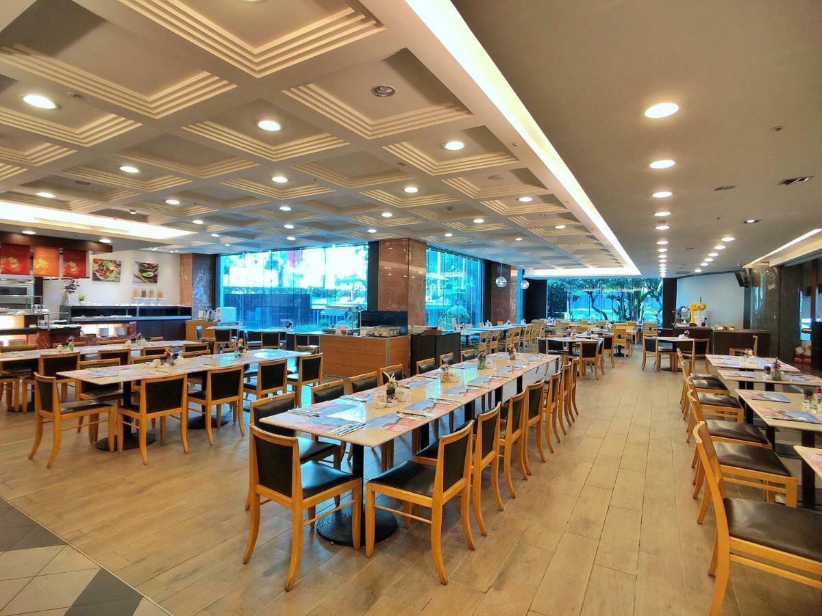 Evergreen Laurel Hotel - Taichung Extérieur photo The photo shows the interior of a restaurant. It features a spacious dining area with several wooden tables and chairs arranged in rows. The floor has a light wood finish, complementing the stylish design. The ceiling is decorated with a modern patte