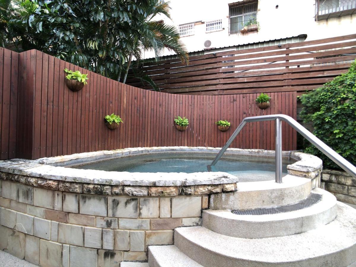 Evergreen Laurel Hotel - Taichung Extérieur photo The photo shows a small outdoor hot tub or spa area. It's surrounded by a wooden fence, with several planters containing greenery attached to the wall. The hot tub is round, with a stone border, and there are steps leading up to it with a stainless s