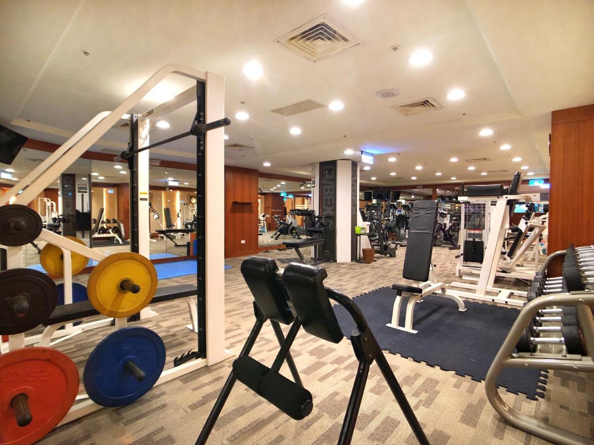 Evergreen Laurel Hotel - Taichung Extérieur photo The photo shows a gym interior with various workout equipment. On the left, there are weights of different colors stacked on a weight rack. In the foreground, there's a bench for exercises, and in the background, multiple machines for strength traini